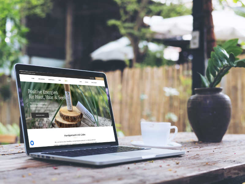 Mockup image of laptop with blank white screen and coffee cup on vintage wooden table in nature outdoor park